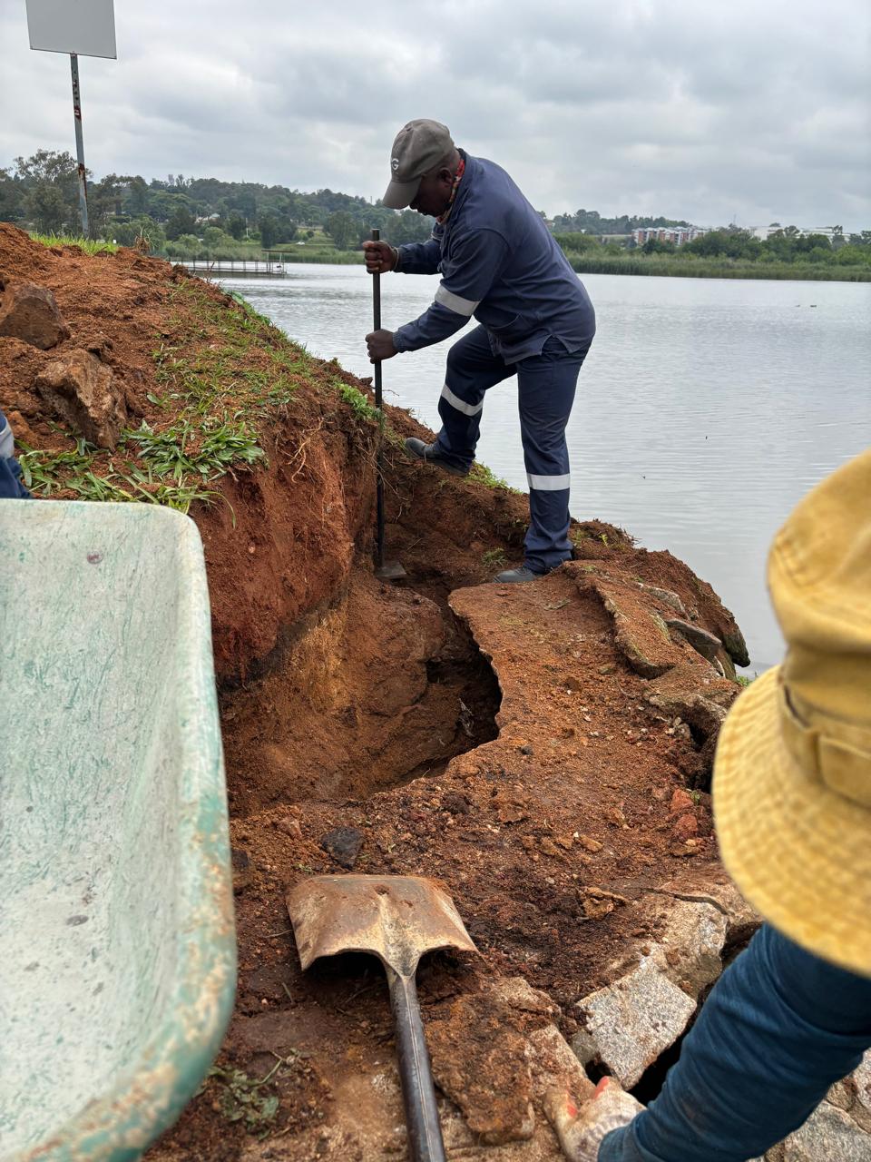 Worker probing the excavated cavity at the dam wall with a steel bar