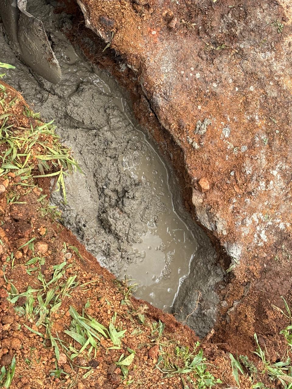 Wet concrete placed in the excavated trench beside the dam wall