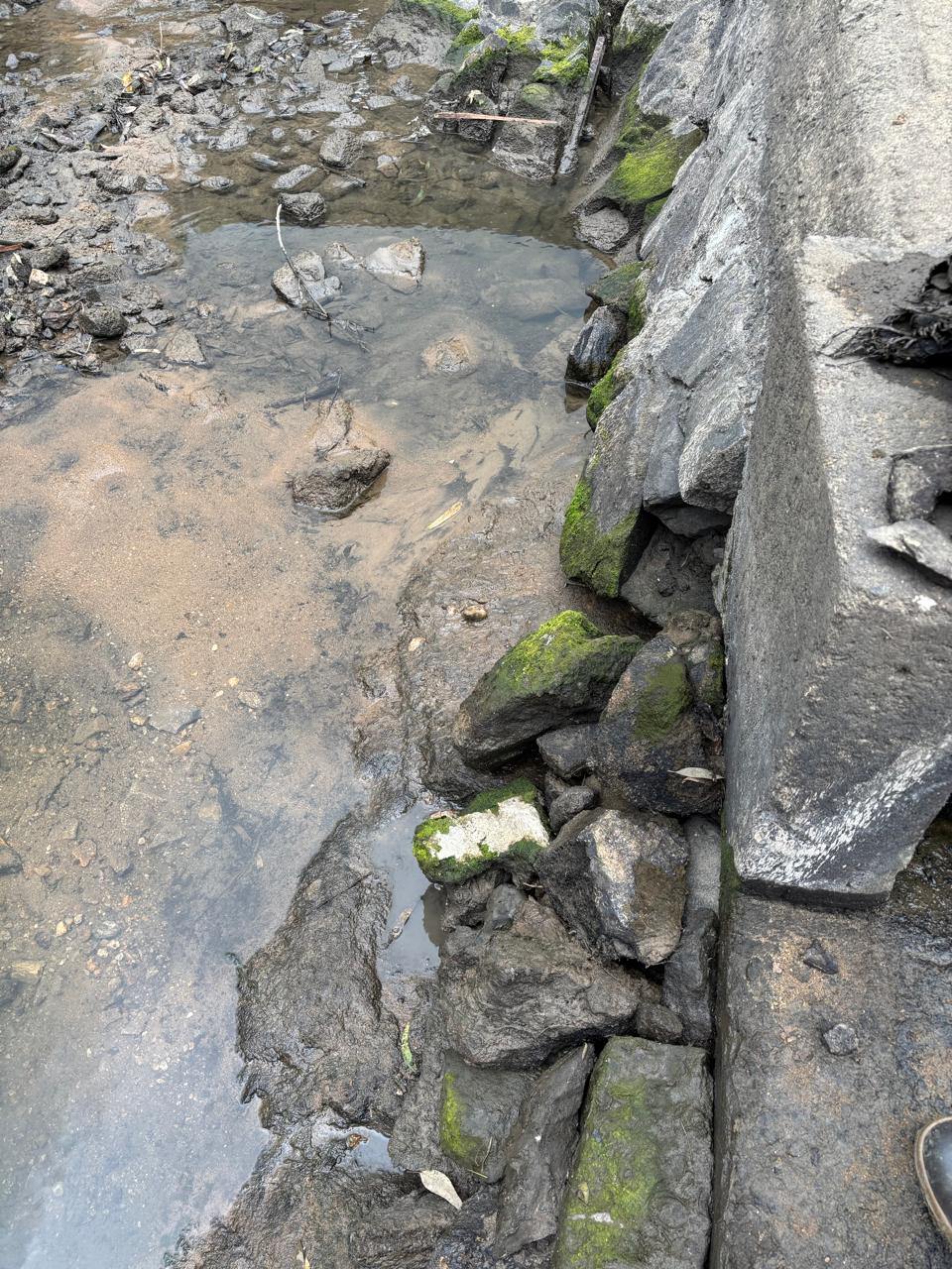 Loose rock and scour along the toe of the spillway wall