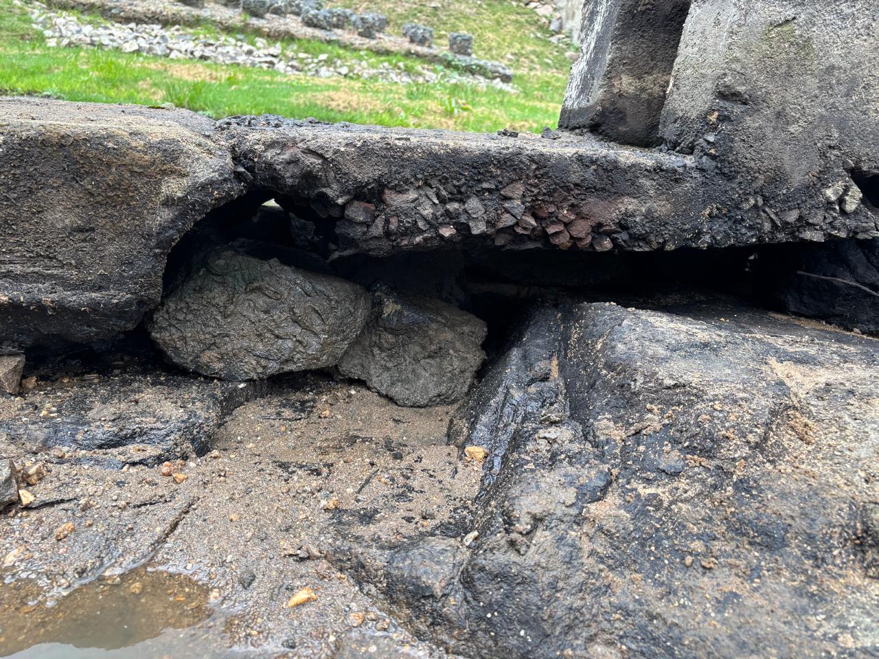 Spillway concrete undermined by water flow, leaving a void beneath the slab