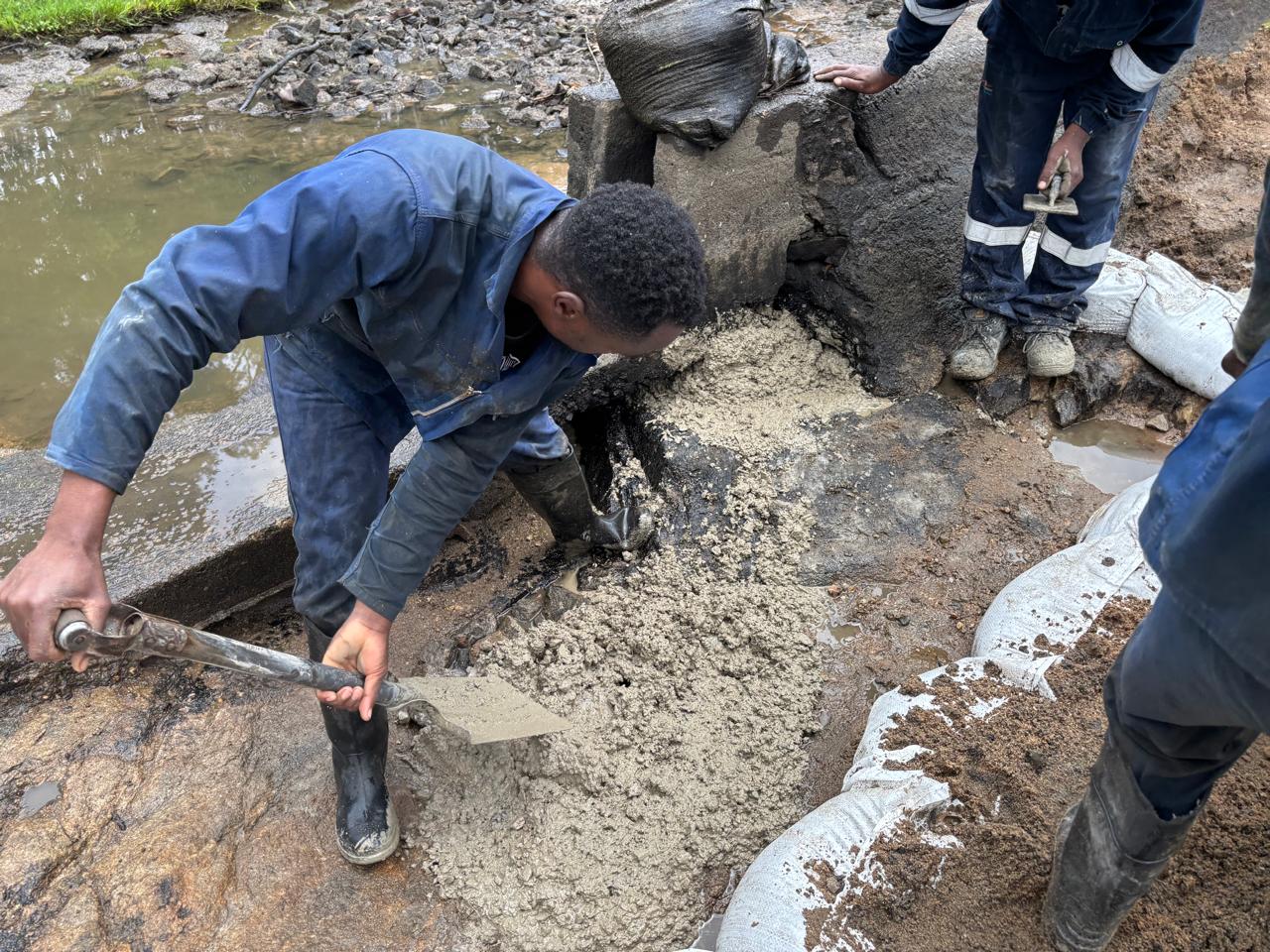 Workers placing new concrete into a prepared repair section at a spillway