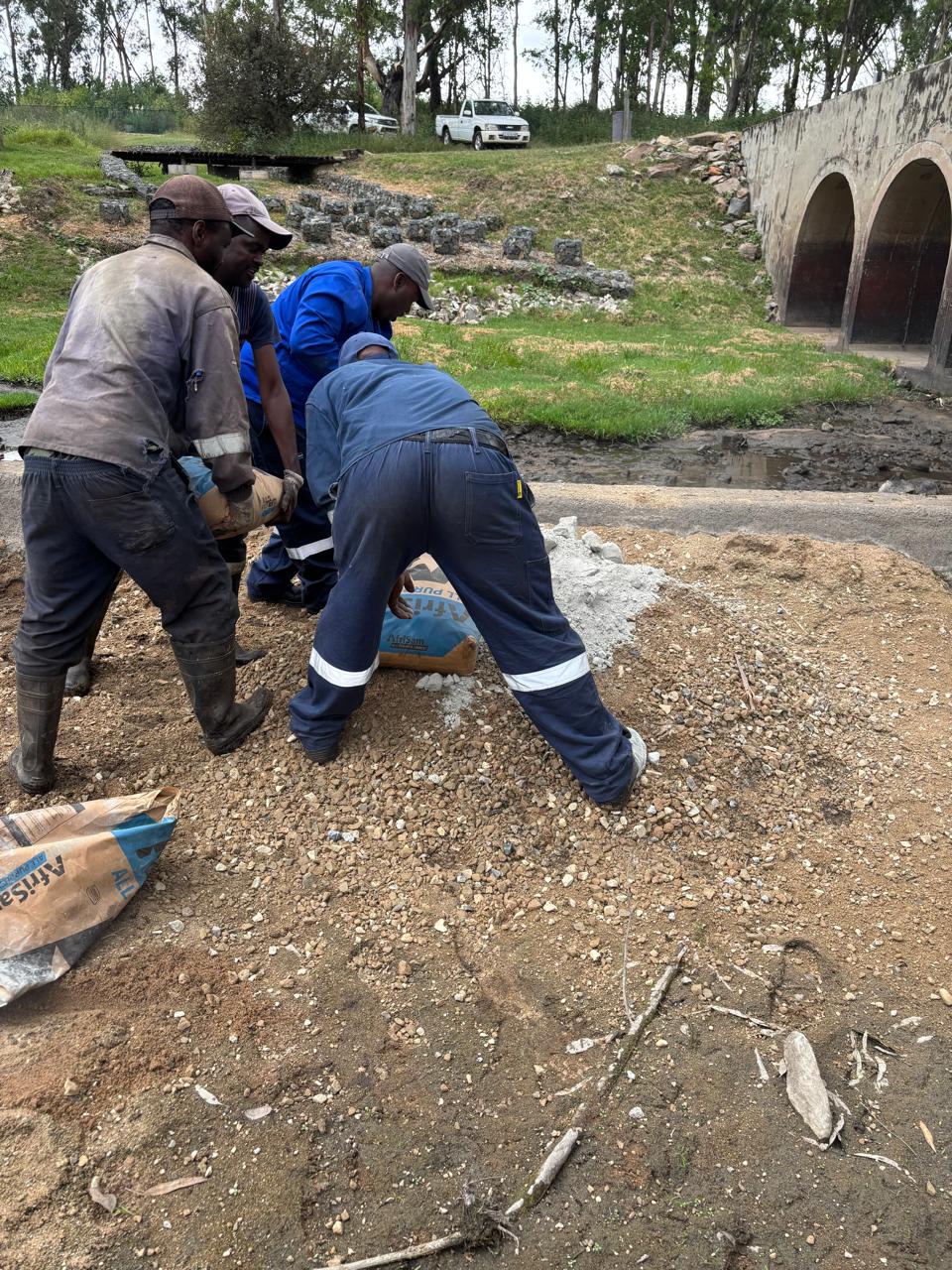 Workers mixing concrete on site beside the spillway
