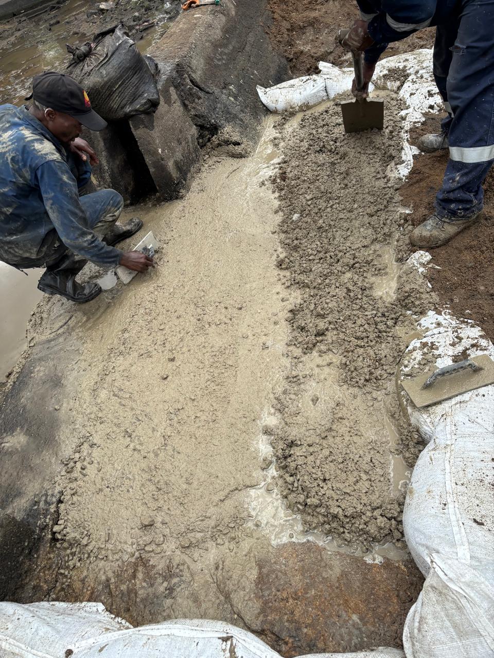 Concrete spread and levelled by trowel inside the sandbagged repair area